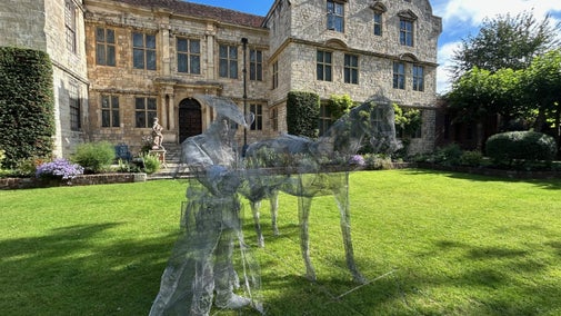 Large mesh statues of a horse and a Highwayman in a garden with a stone house behind